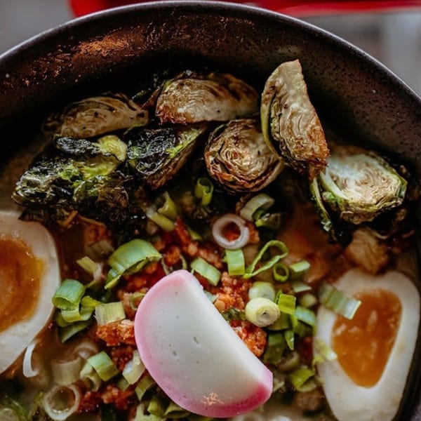 Close-up of Boru Ramen with roasted brussels sprouts, soft-boiled egg, scallions, and fish cake.