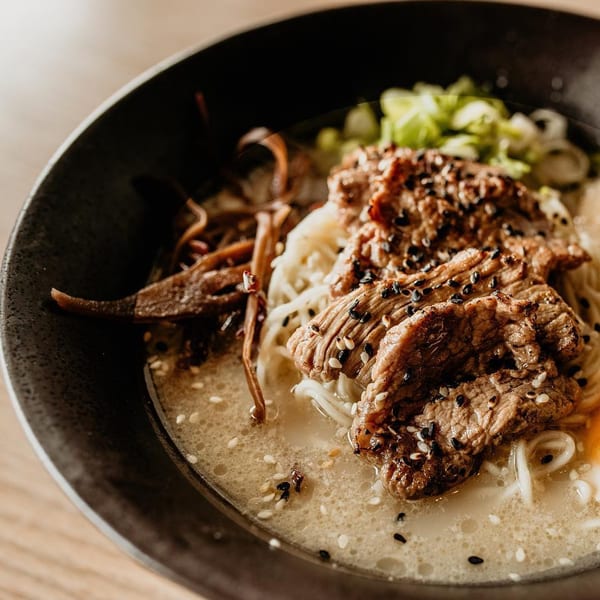 Close-up of Boru Ramen's beef ramen bowl with noodles, broth, green onions, and sesame seeds.