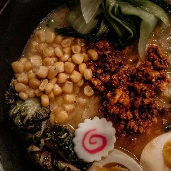 Close-up of Boru Ramen with corn, ground meat, bok choy, narutomaki, and a soft-boiled egg.